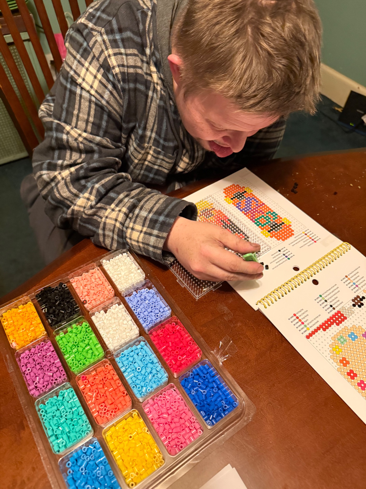 Matt working at a table with organized trays of colorful fusion beads