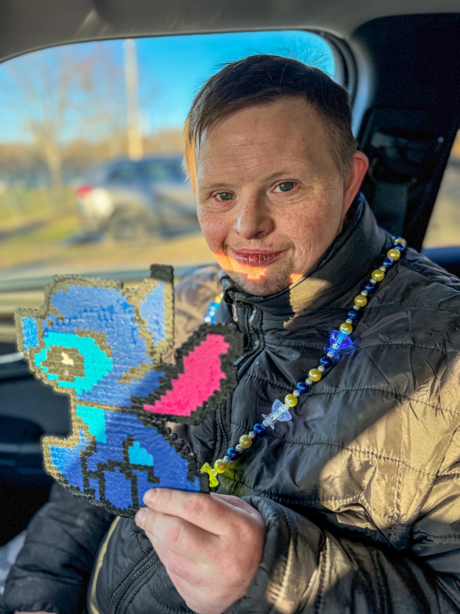 Matt smiling and holding a large blue and pink fusion-bead character
